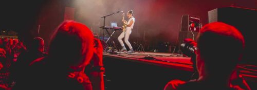 Concert avec musicienne jouant de la guitare sur scène.