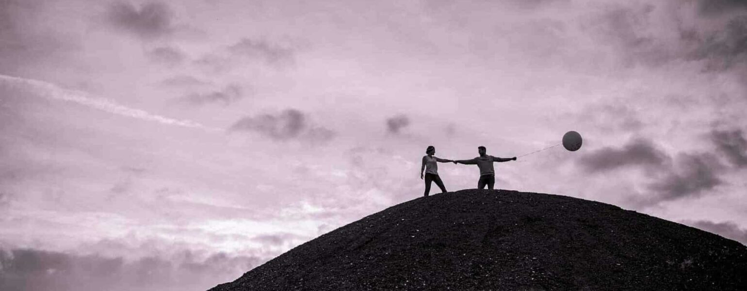 Deux personnes avec ballon sur colline sombre.