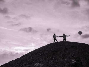Deux personnes avec ballon sur colline sombre.