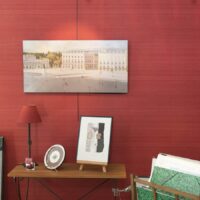 Salle d'exposition avec plusieurs tableaux sur murs rouges.