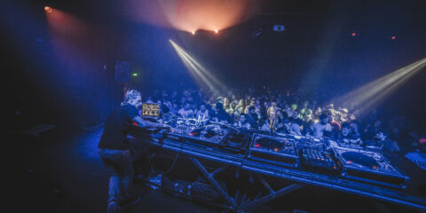 Scène de DJ en pleine performance lors d’une soirée Techno Story, éclairages intenses et foule animée.