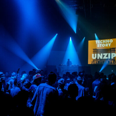 Ambiance en pleine fête électro pendant une soirée Techno Story, lumière sombre et public dansant.