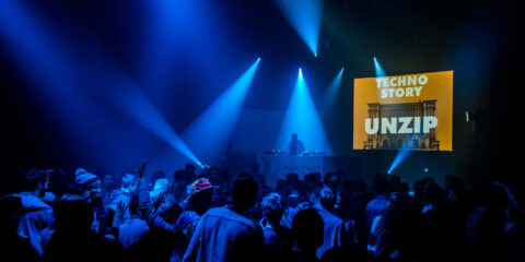 Ambiance en pleine fête électro pendant une soirée Techno Story, lumière sombre et public dansant.