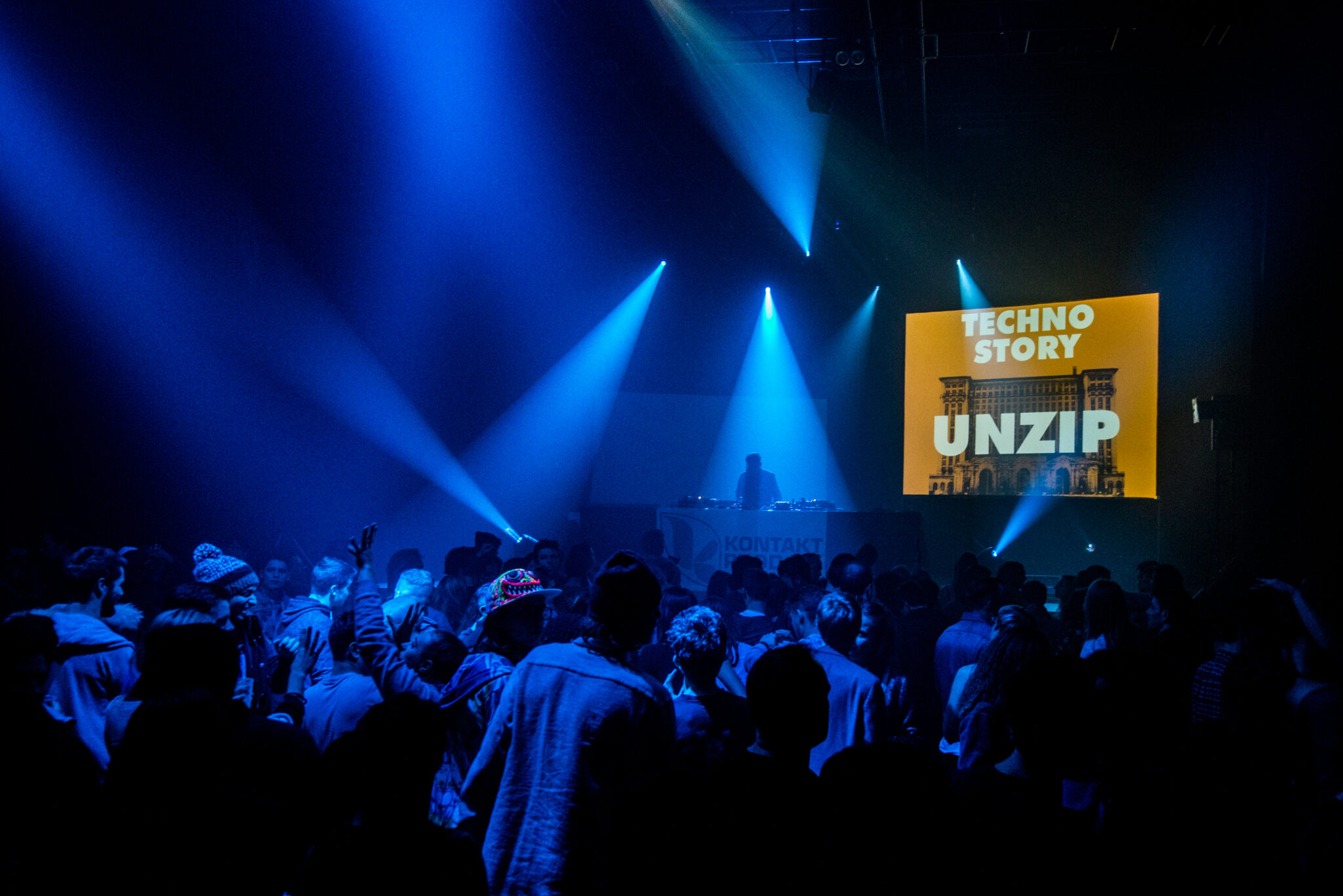 Ambiance en pleine fête électro pendant une soirée Techno Story, lumière sombre et public dansant.