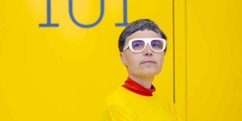 Personne en lunettes blanches sur fond jaune vif.