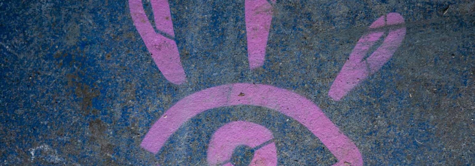 Graffiti œil rose sur mur bleu.