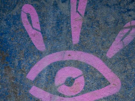 Graffiti œil rose sur mur bleu.
