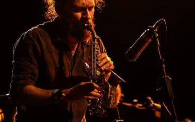 Musicien jouant du saxophone sur scène éclairée.