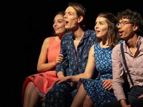 Quatre personnes souriantes sur une scène de théâtre.