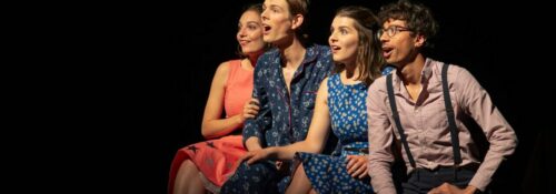 Quatre personnes souriantes sur une scène de théâtre.