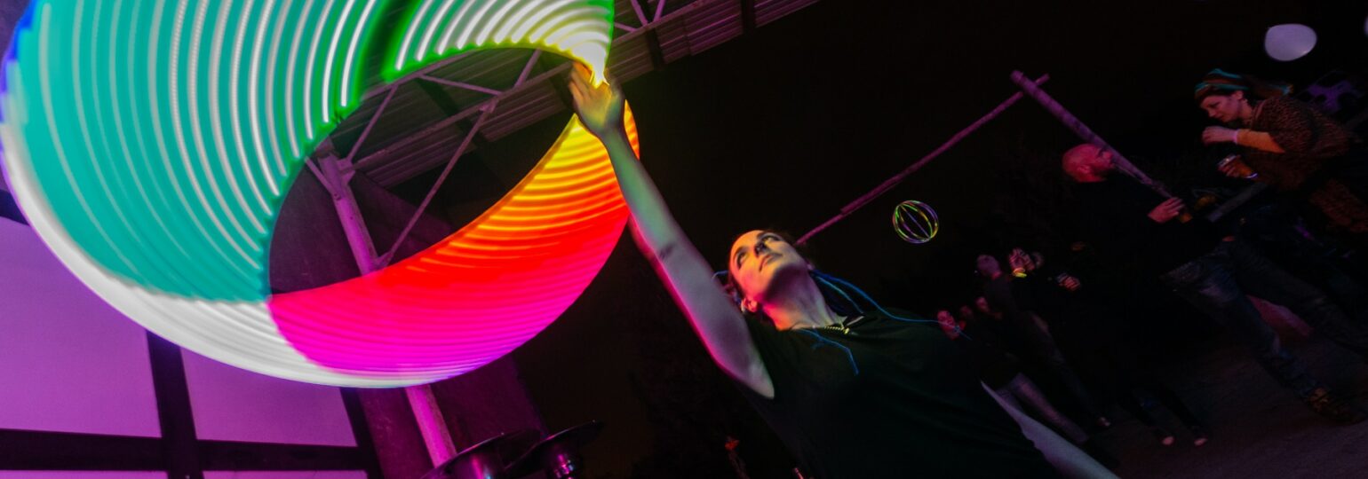 Personne jonglant avec cercle lumineux coloré.