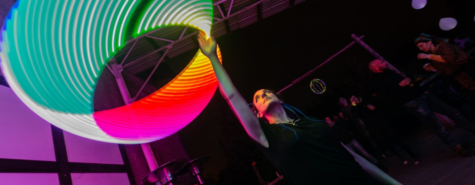 Personne jonglant avec cercle lumineux coloré.