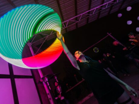 Personne jonglant avec cercle lumineux coloré.