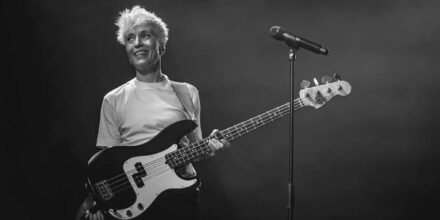 Musicienne souriante avec guitare basse sur scène.