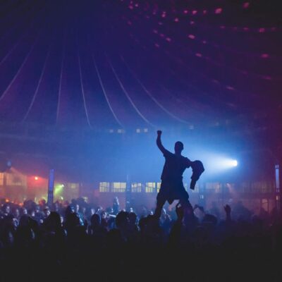 Foule dansante sous lumière colorée en soirée.