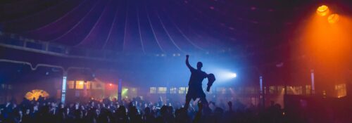 Foule dansante sous lumière colorée en soirée.