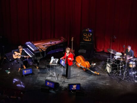 Concert avec musiciens sur scène, instruments variés.