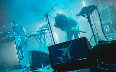 Concert avec synthétiseurs et guitare sur scène.