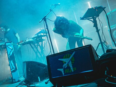 Concert avec synthétiseurs et guitare sur scène.