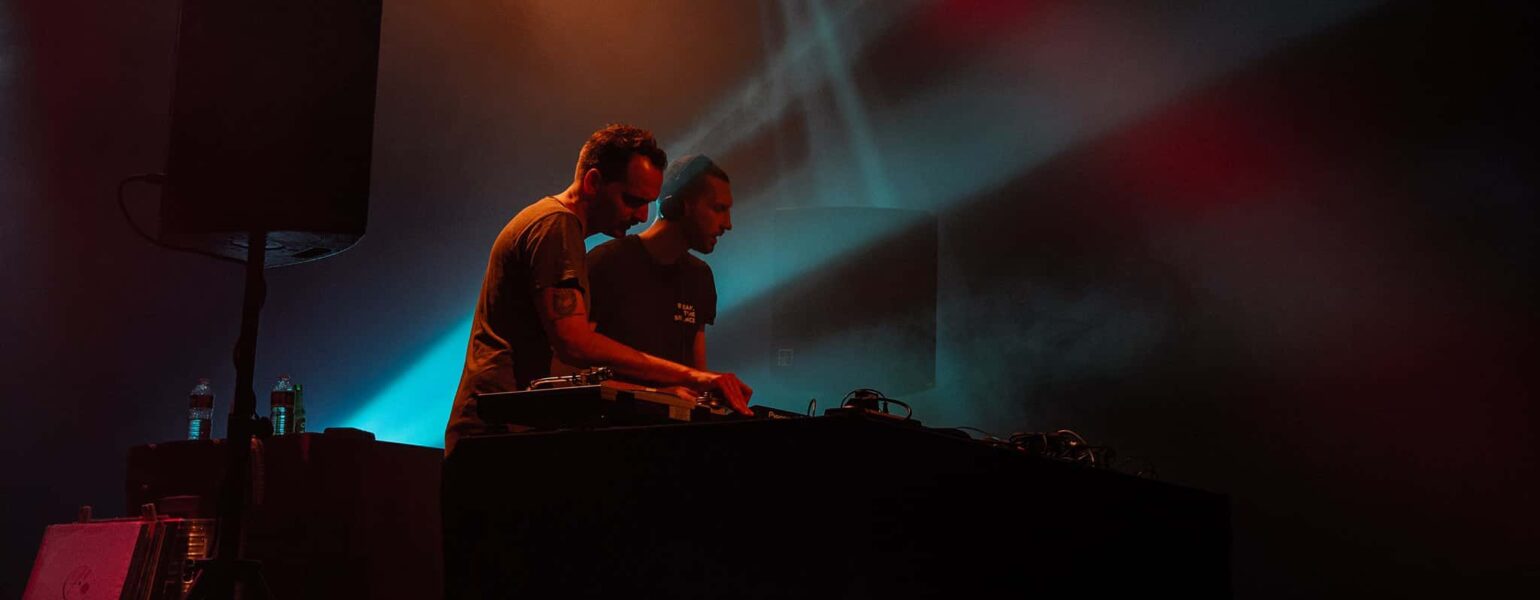 Deux DJ sur scène avec lumières colorées.