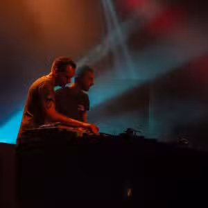 Deux DJ sur scène avec lumières colorées.