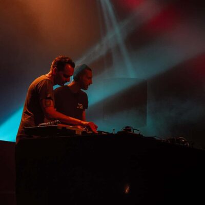 Deux DJ sur scène avec lumières colorées.