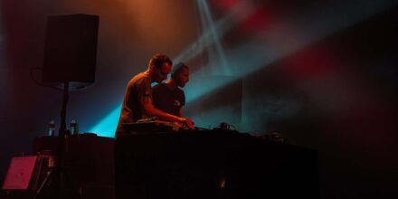 Deux DJ sur scène avec lumières colorées.