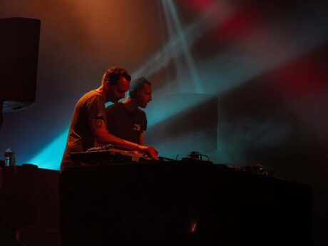Deux DJ sur scène avec lumières colorées.