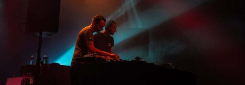 Deux DJ sur scène avec lumières colorées.