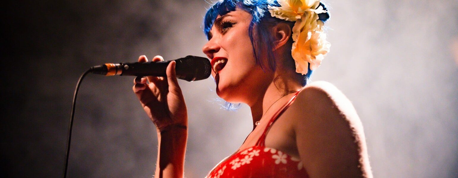 Chanteuse sur scène avec micro et cheveux bleus