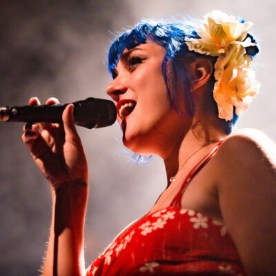 Chanteuse sur scène avec micro et cheveux bleus