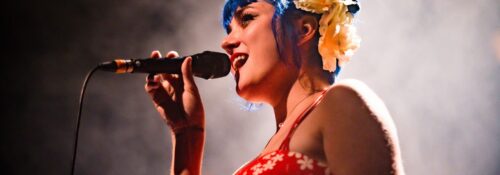 Chanteuse sur scène avec micro et cheveux bleus