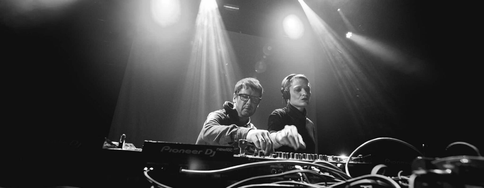 Deux DJ mixant sur scène, éclairage intense.