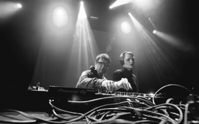 Deux DJ mixant sur scène, éclairage intense.