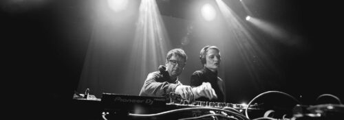 Deux DJ mixant sur scène, éclairage intense.