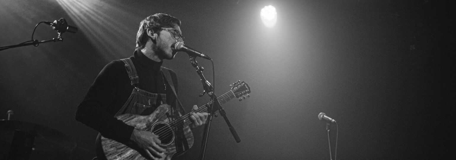 Chanteur jouant de la guitare sur scène.