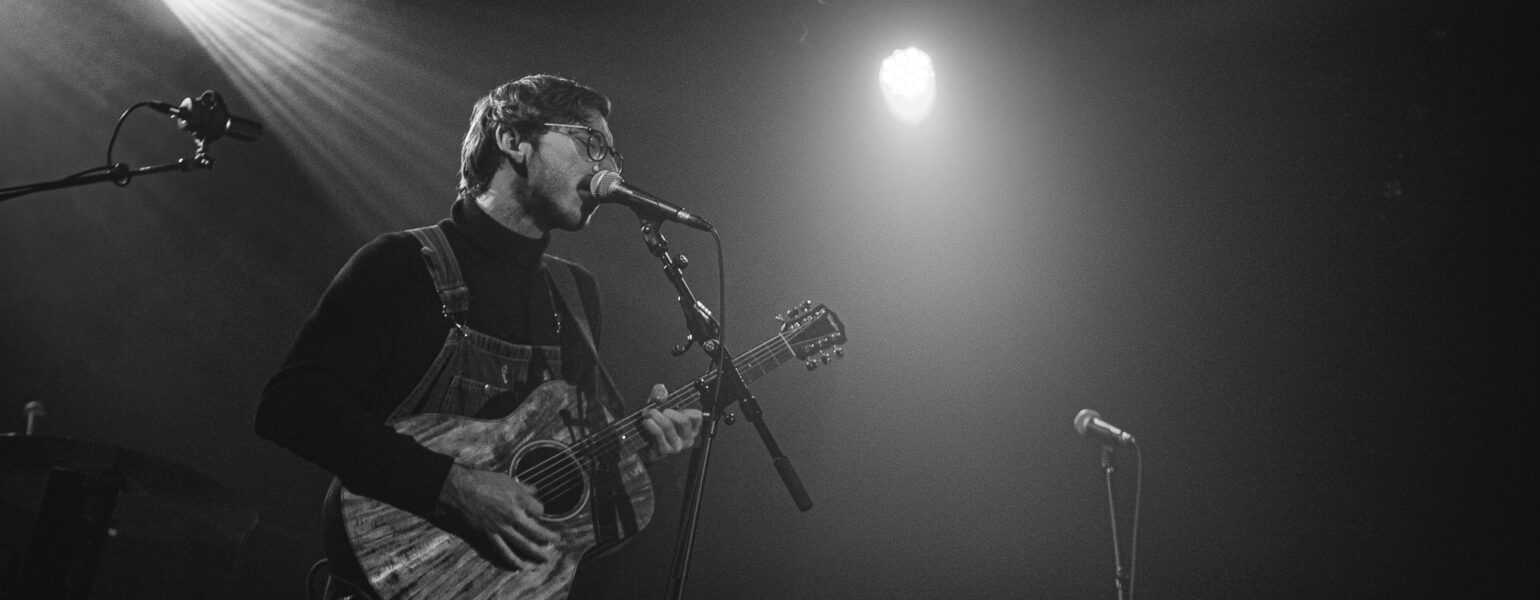 Chanteur jouant de la guitare sur scène.