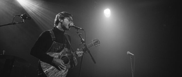 Chanteur jouant de la guitare sur scène.