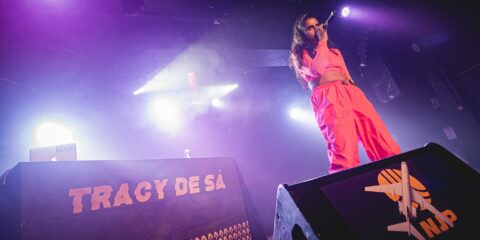 Chanteuse sur scène avec éclairage violet vif.