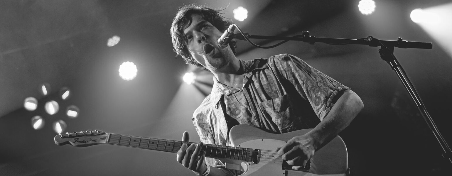 Homme jouant de la guitare sur scène.