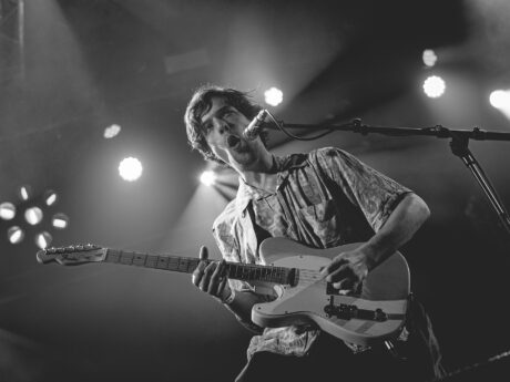 Homme jouant de la guitare sur scène.