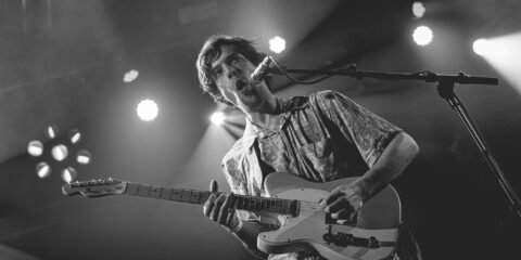 Homme jouant de la guitare sur scène.