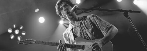 Homme jouant de la guitare sur scène.