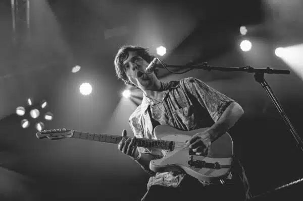 Homme jouant de la guitare sur scène.