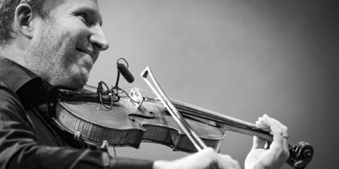 Homme jouant du violon sur scène.