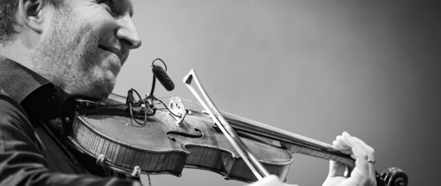 Homme jouant du violon sur scène.