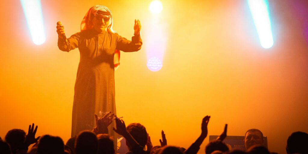 Artiste sur scène, éclairage coloré, public enthousiaste.