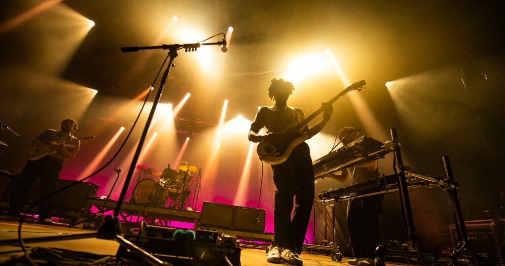 Groupe de musique en concert avec éclairage coloré.