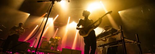 Groupe de musique en concert avec éclairage coloré.