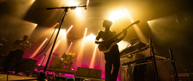 Groupe de musique en concert avec éclairage coloré.